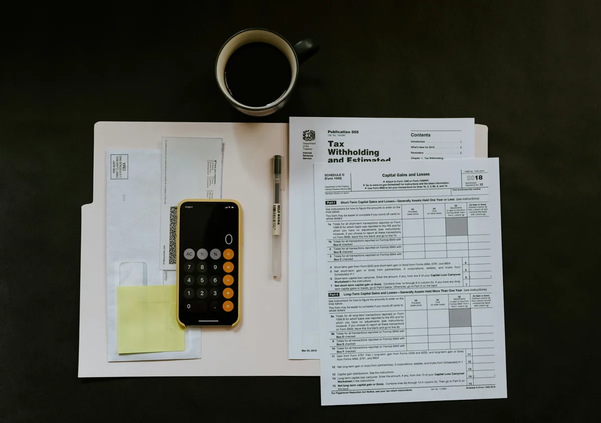 How much tax will I owe in 2026 — IRS tax documents, calculator and withholding forms on a desk
